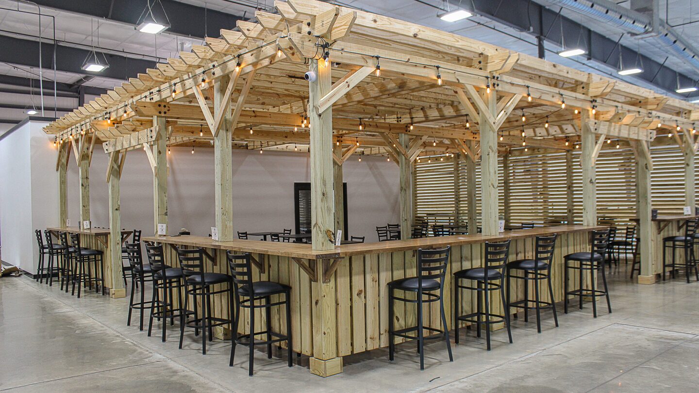 The pergola and its long bar at Dual Cities NWA set up and ready for a group, string lights overhead.