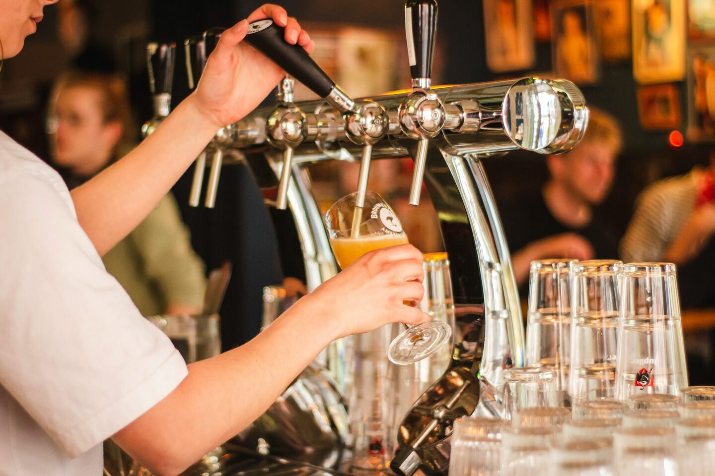 Golden draft beer in a glass on a wood bar.