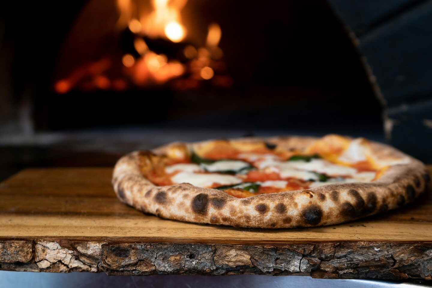 A wood-fired pizza on a wooden board, fresh from the oven.