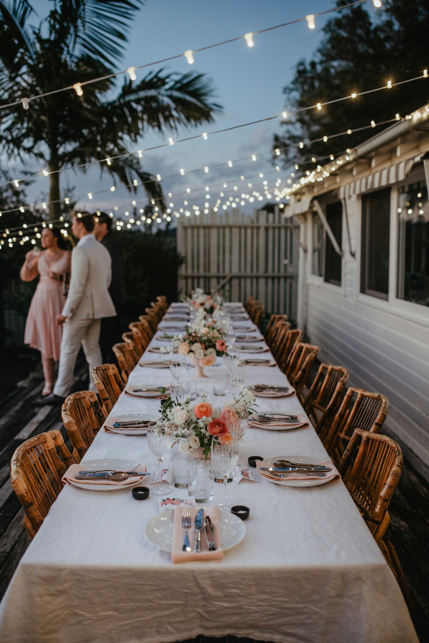 Pergola at night during an event, string lights on, people gathered.