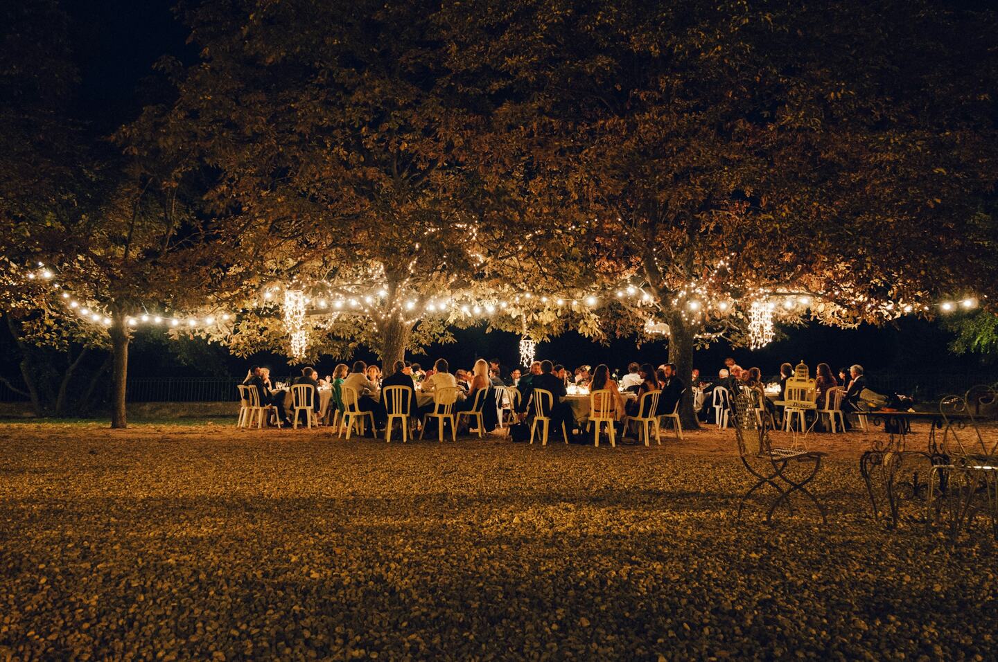 Pergola at dusk with string lights and a set table for a private event.
