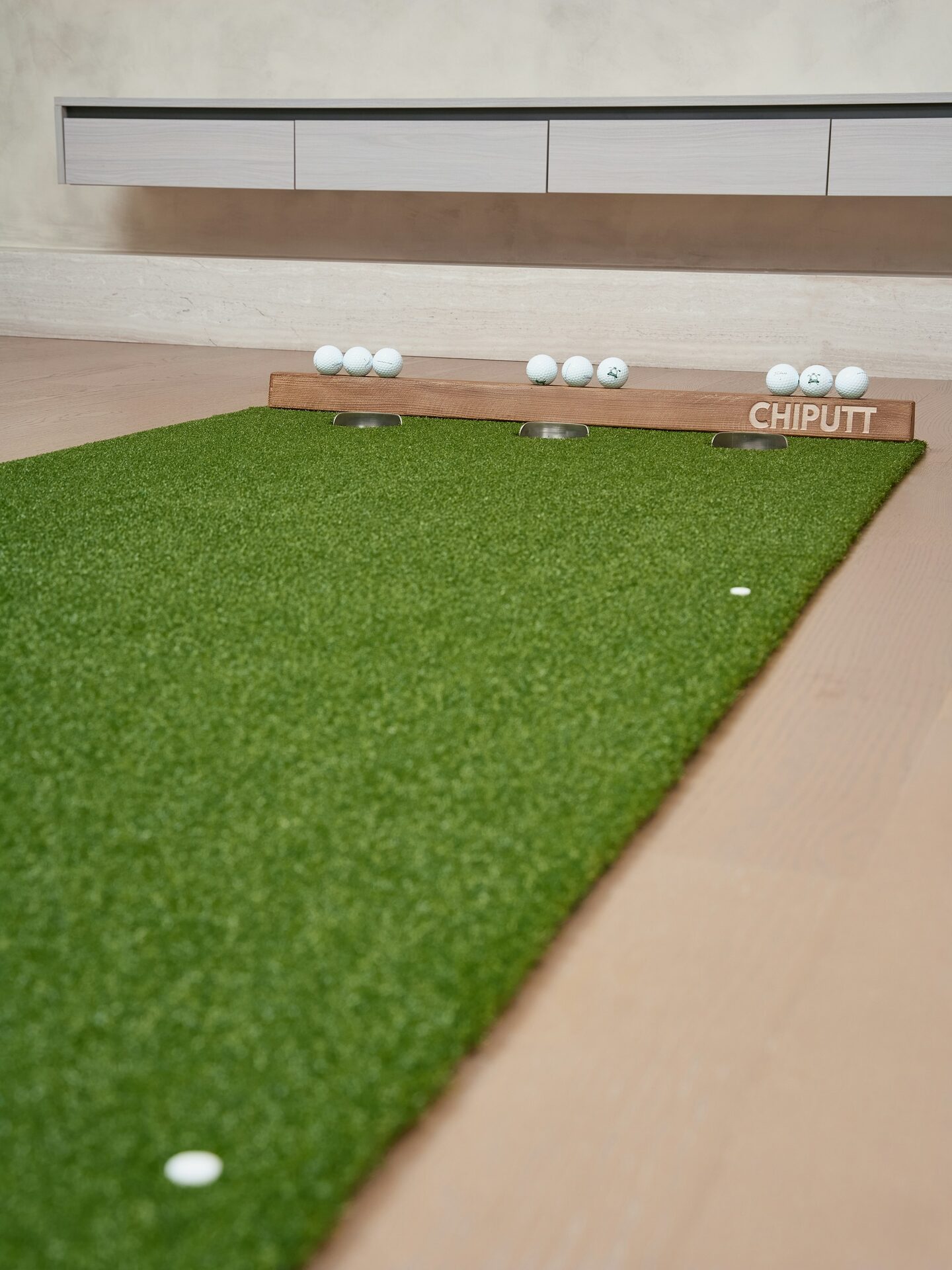Dim golf simulator bay with screen glow and a person watching a tee shot.