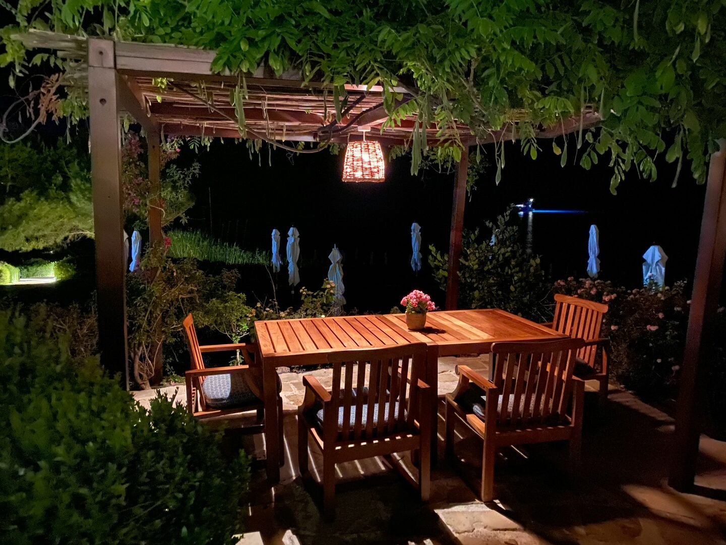 An indoor wood pergola at dusk with string lights, set tables, and warm interior light.